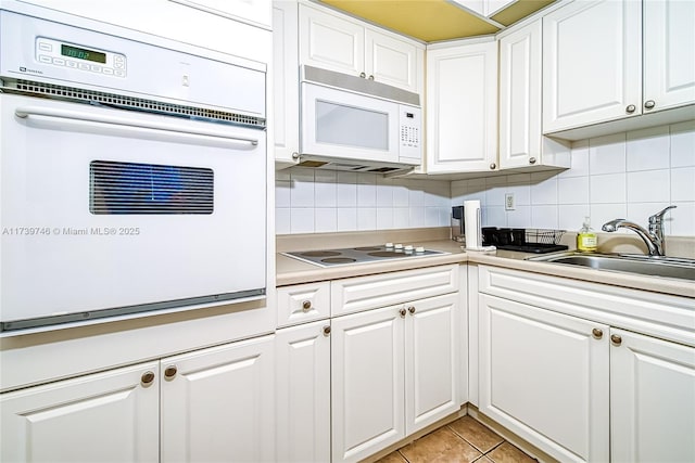 kitchen with white cabinetry, sink, white appliances, and tasteful backsplash