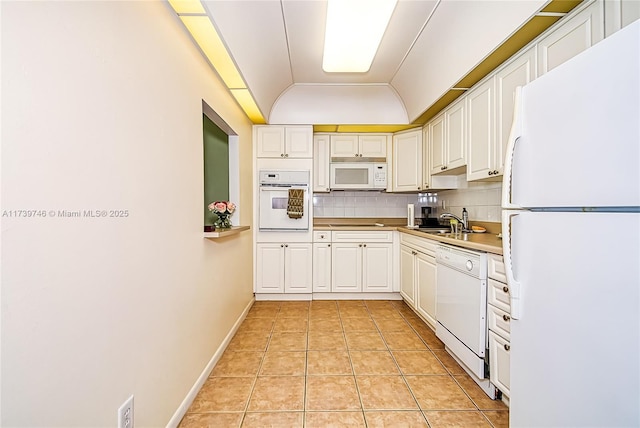 kitchen with light tile patterned floors, white appliances, sink, backsplash, and vaulted ceiling