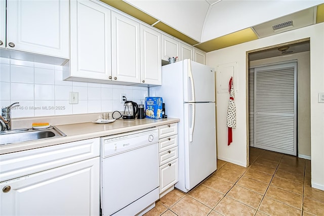 kitchen with light tile patterned floors, white appliances, sink, white cabinetry, and decorative backsplash