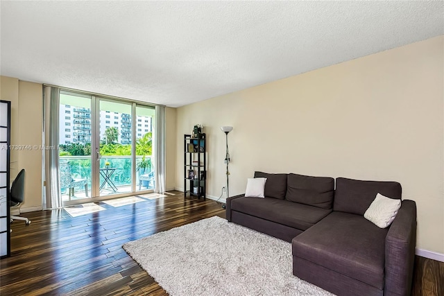 living room with dark hardwood / wood-style floors, a textured ceiling, and a wall of windows