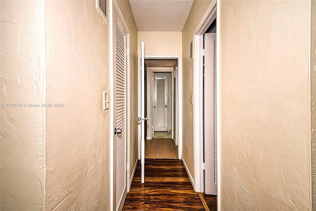 hall with dark hardwood / wood-style floors and a textured ceiling