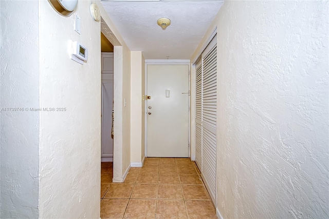 hallway with light tile patterned flooring and a textured ceiling