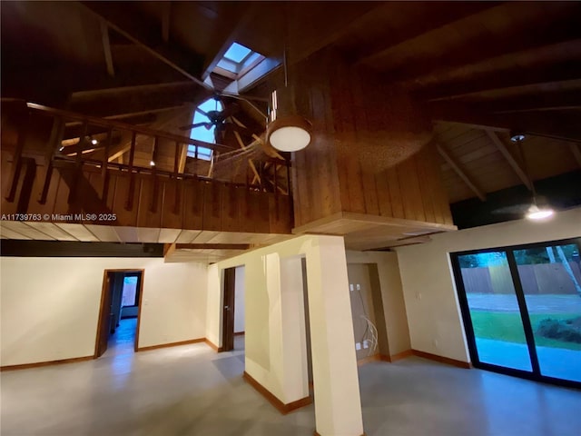 interior space with concrete flooring, beam ceiling, a skylight, and high vaulted ceiling