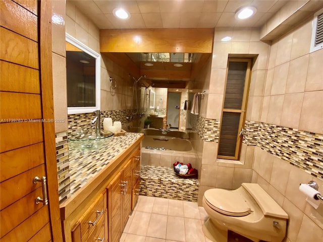 bathroom with a tub to relax in, tile patterned floors, toilet, tasteful backsplash, and tile walls