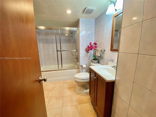 full bathroom featuring toilet, tile walls, a textured ceiling, vanity, and tile patterned flooring