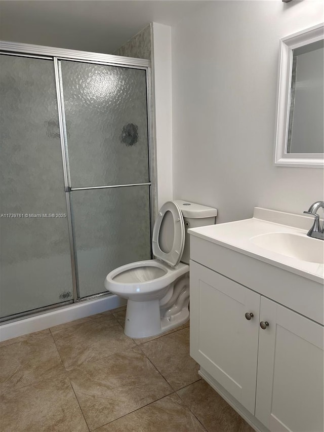 bathroom with tile patterned floors, vanity, toilet, and a shower with shower door