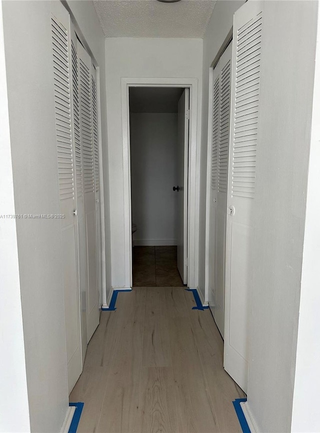 hall featuring a textured ceiling and light hardwood / wood-style flooring