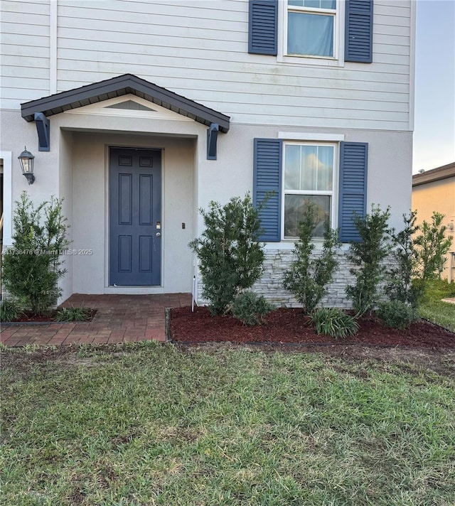 view of exterior entry featuring a lawn