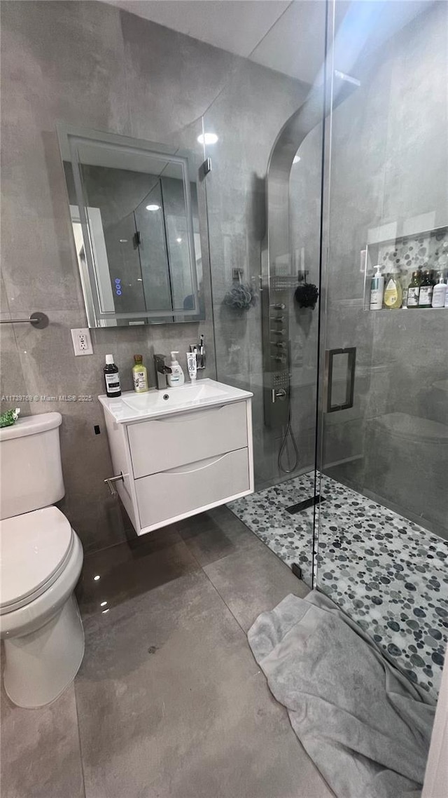 bathroom featuring tile walls, tile patterned flooring, vanity, an enclosed shower, and toilet