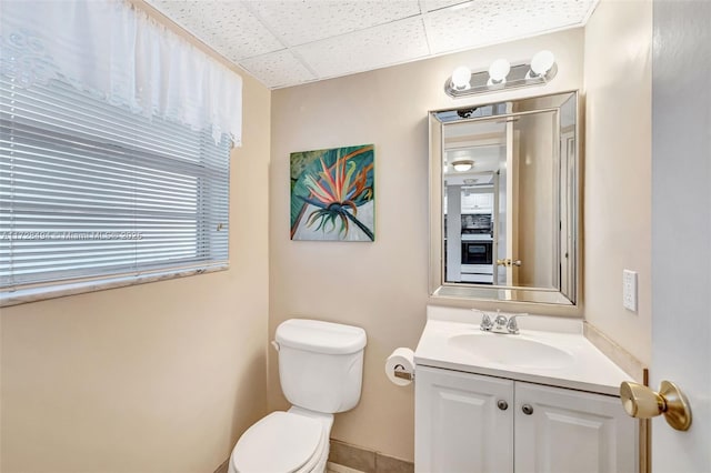 bathroom featuring vanity, a drop ceiling, and toilet