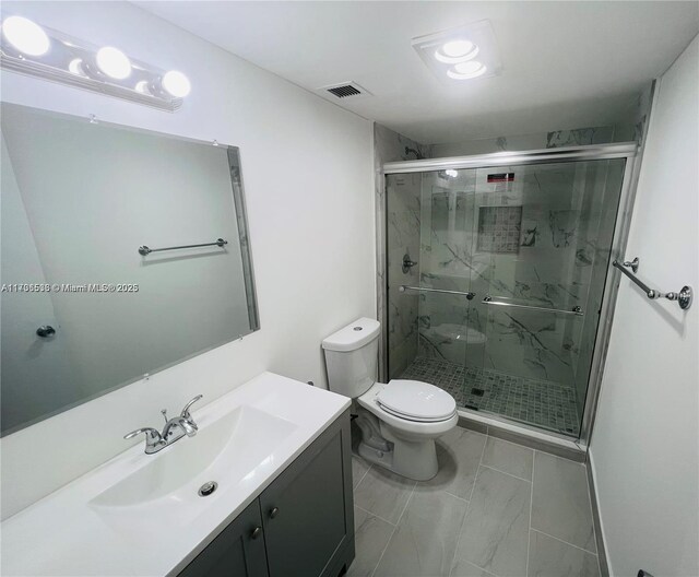 bathroom with vanity, toilet, and a shower with door