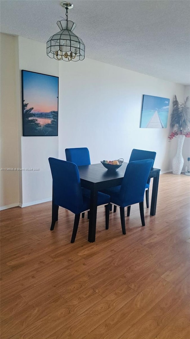 dining space with wood-type flooring and a textured ceiling