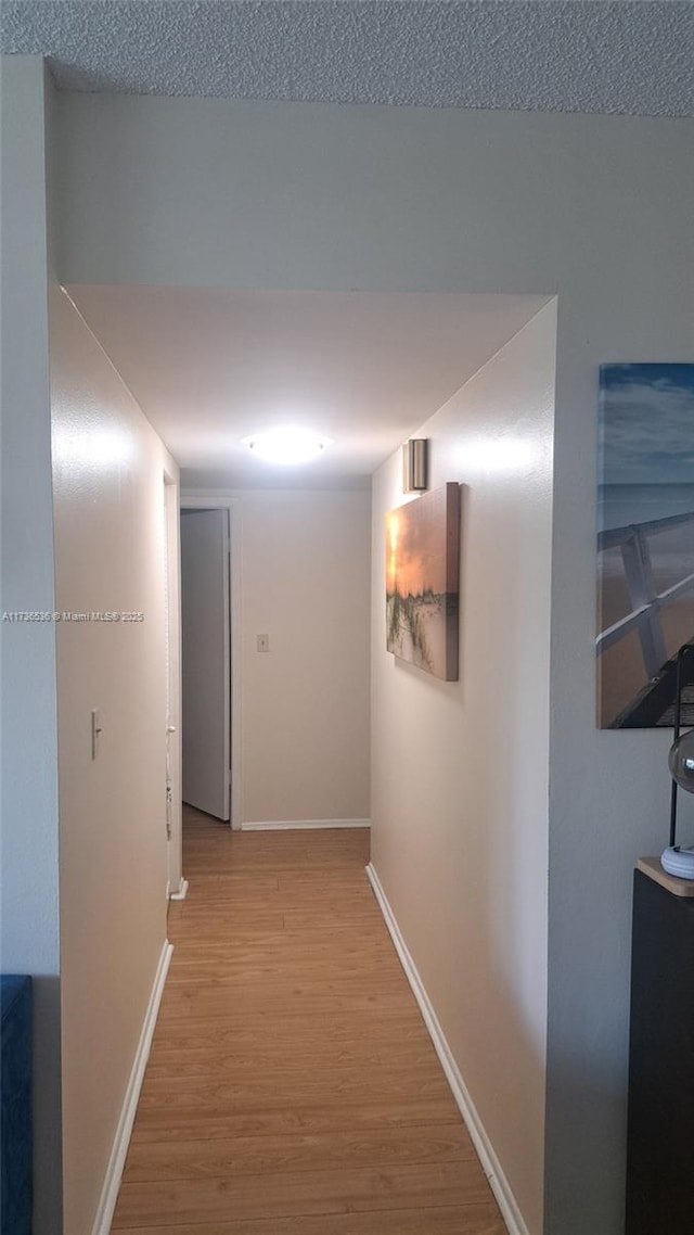 hall featuring light hardwood / wood-style flooring and a textured ceiling