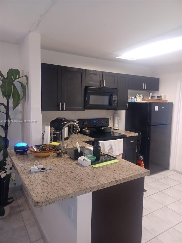 kitchen with kitchen peninsula, light tile patterned floors, light stone countertops, and black appliances