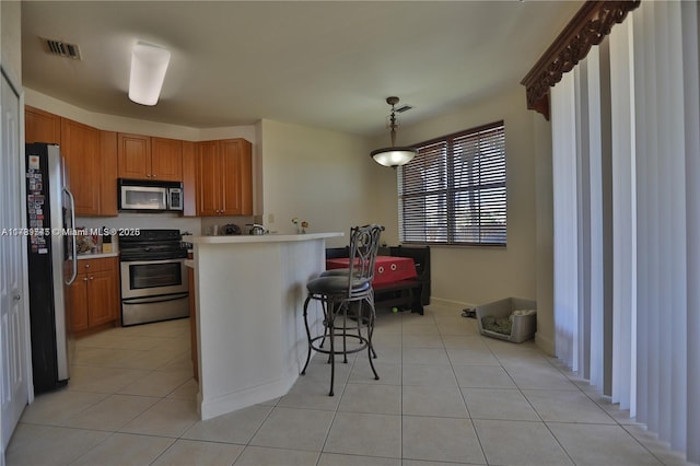 kitchen featuring stainless steel appliances, light tile patterned floors, a kitchen breakfast bar, and kitchen peninsula