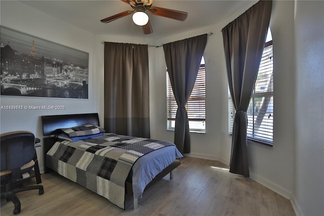 bedroom featuring multiple windows, wood-type flooring, and ceiling fan