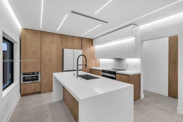 kitchen with sink, white fridge, a kitchen island with sink, stainless steel oven, and black / electric stove