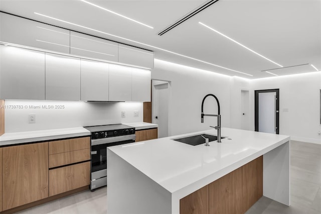 kitchen featuring a kitchen island with sink, electric range oven, sink, and white cabinets