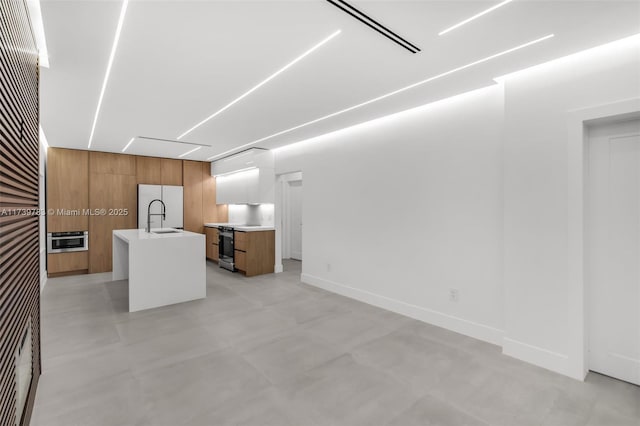 kitchen featuring wooden walls, sink, white fridge, a kitchen island with sink, and electric stove