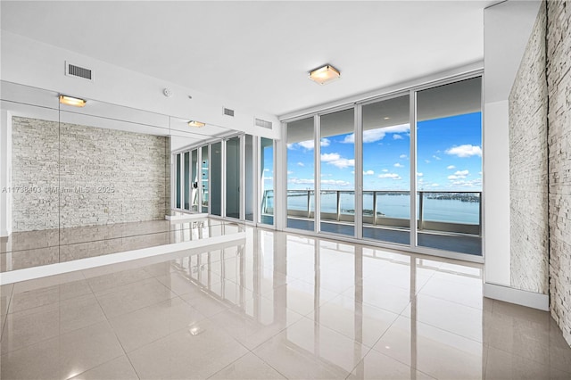 tiled empty room with a wall of windows and a water view