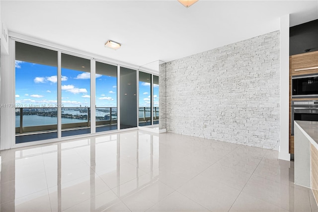 empty room with tile patterned flooring, expansive windows, and a water view