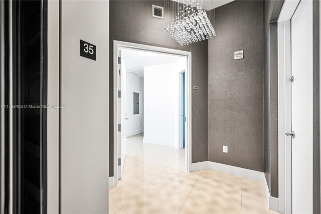 hallway featuring an inviting chandelier, electric panel, and light tile patterned floors