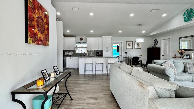 living room featuring lofted ceiling, light wood-style flooring, and recessed lighting