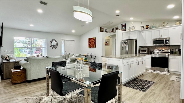 kitchen with open floor plan, a center island, stainless steel appliances, arched walkways, and light wood finished floors