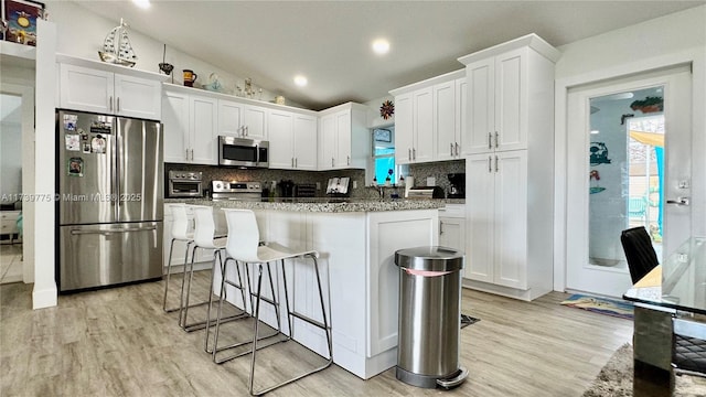 kitchen with decorative backsplash, vaulted ceiling, a kitchen breakfast bar, and stainless steel appliances