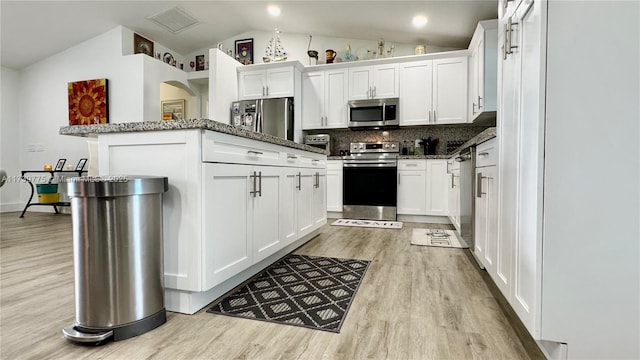 kitchen featuring light wood-style flooring, white cabinetry, stainless steel appliances, and lofted ceiling