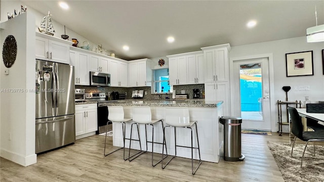 kitchen with backsplash, stainless steel appliances, vaulted ceiling, and white cabinets