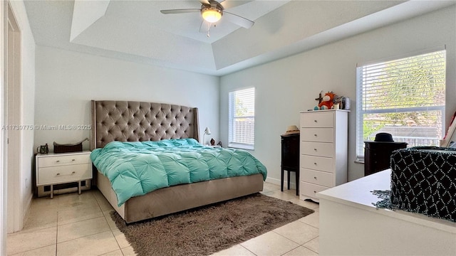 tiled bedroom with a raised ceiling and ceiling fan