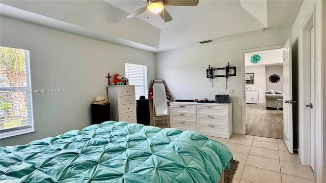 bedroom with ceiling fan, a raised ceiling, and light tile patterned floors