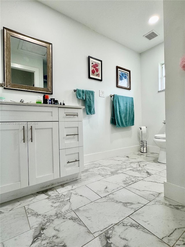 bathroom featuring visible vents, baseboards, toilet, marble finish floor, and vanity