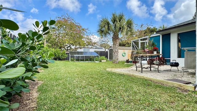 view of yard with an outdoor structure, a storage unit, fence, and a patio area