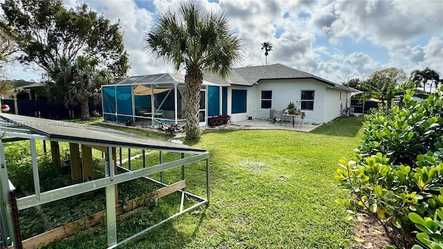 rear view of property with a patio, fence, a yard, stucco siding, and a lanai