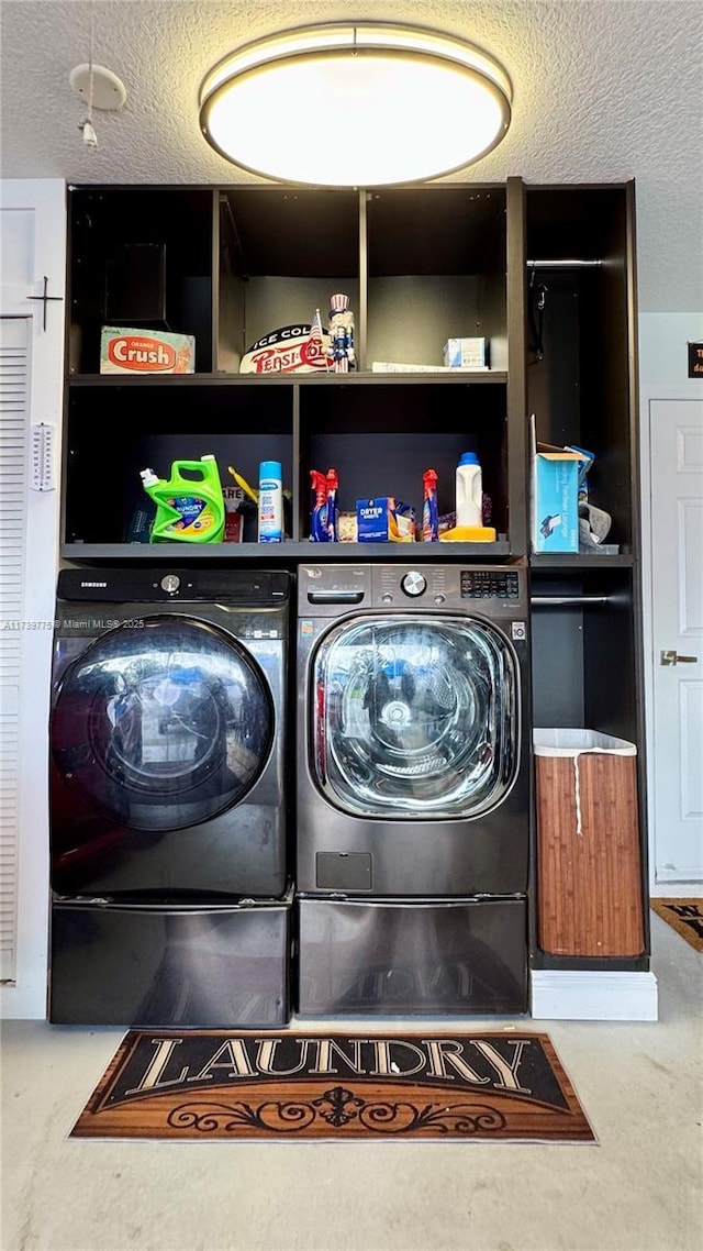 clothes washing area featuring washing machine and clothes dryer and a textured ceiling