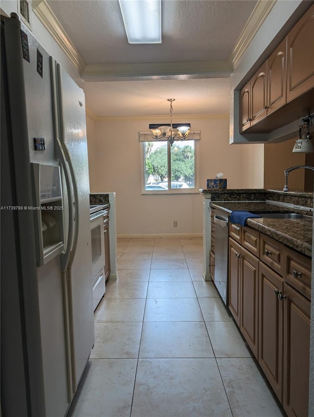 kitchen featuring light tile patterned floors, white appliances, ornamental molding, a textured ceiling, and dark stone counters