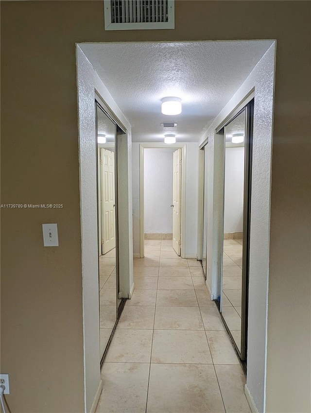 hall with light tile patterned floors and a textured ceiling