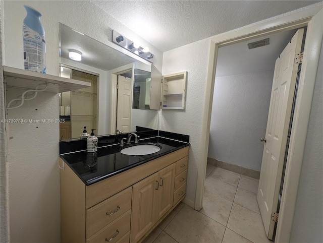 bathroom with tile patterned flooring, vanity, and a textured ceiling