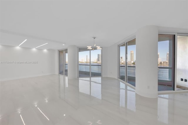 empty room with an inviting chandelier, baseboards, a view of city, and floor to ceiling windows