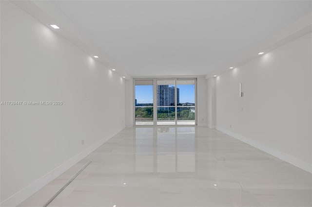 spare room with baseboards and a wall of windows