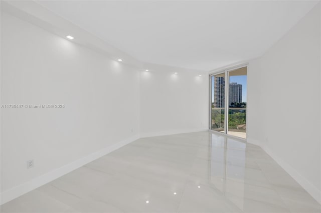 empty room with a view of city, baseboards, and a wall of windows