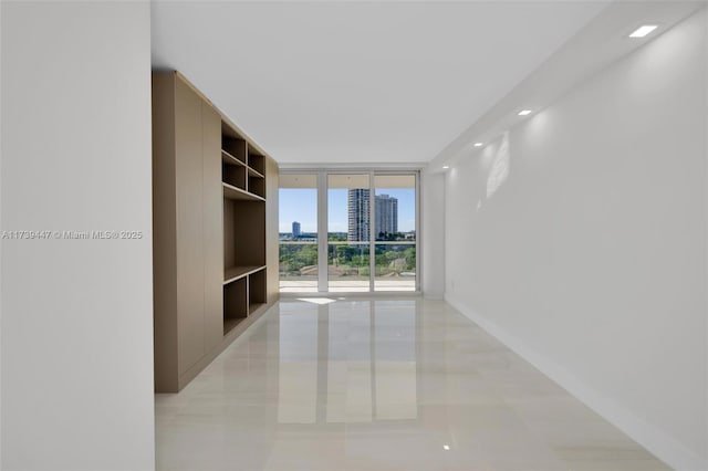 spare room with baseboards, a wall of windows, and a city view