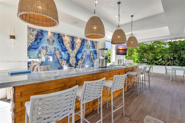 kitchen with a raised ceiling, hanging light fixtures, and wood finished floors