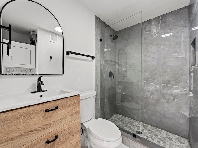 bathroom with a tile shower, vanity, and toilet