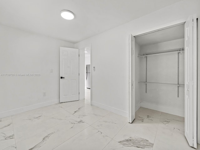 unfurnished bedroom featuring stainless steel fridge and a closet