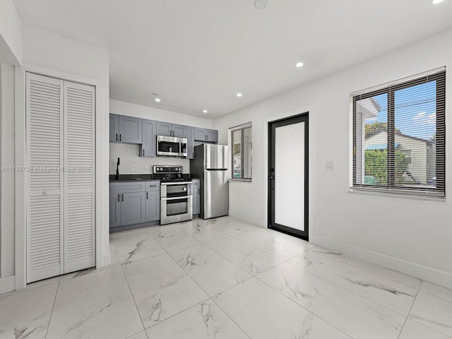 kitchen with a healthy amount of sunlight, appliances with stainless steel finishes, sink, and gray cabinetry