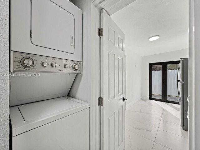 clothes washing area featuring french doors and stacked washer / drying machine