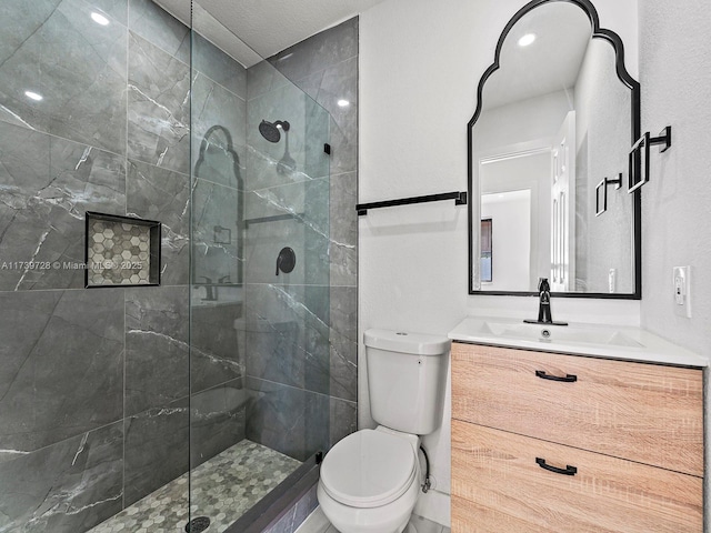 bathroom featuring vanity, a tile shower, and toilet